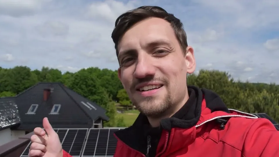 Dawid Jarząbek na dachu klienta przy panelach fotowoltaicznych po latach pracy, kadr z filmu