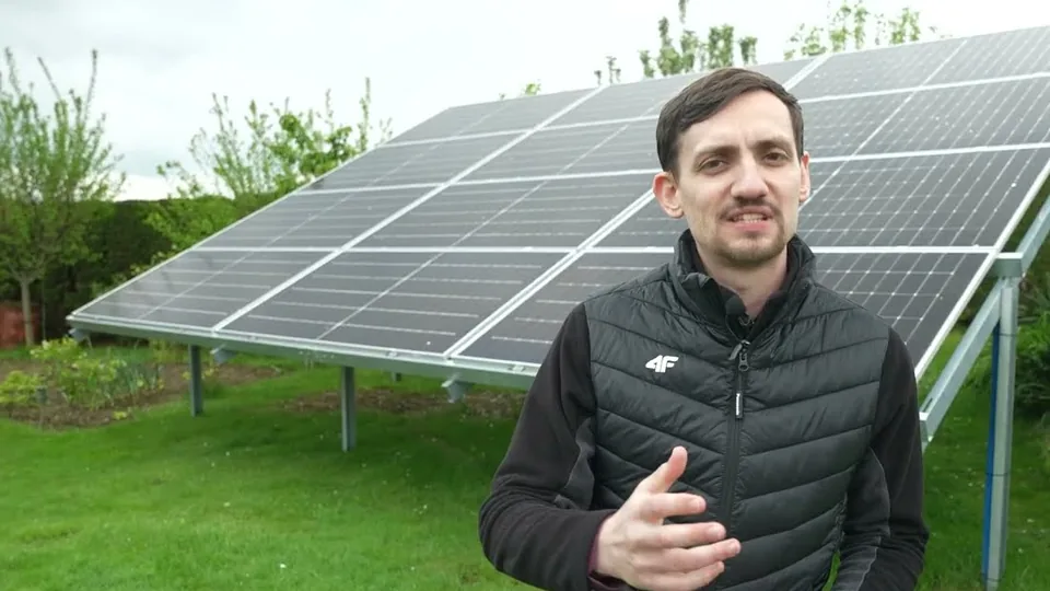 Dawid Jarząbek przed panelami dwustronnymi na konstrukcji na gruncie u klienta z magazynem energii, kadr z filmu