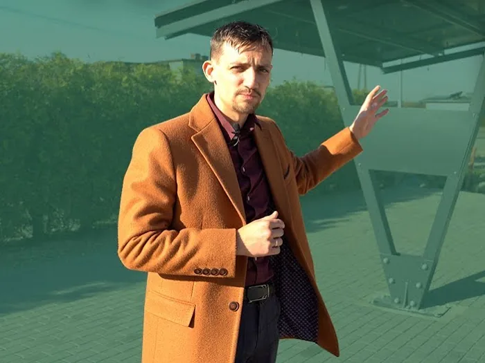 Dawid Jarząbek przy wiacie z panelami fotowoltaicznymi na dachu, kadr z filmu Aslandi
