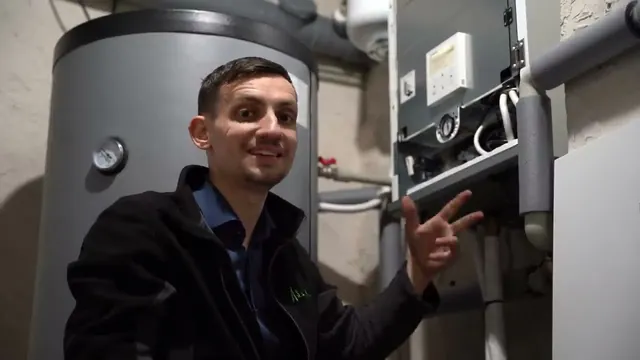 Dawid Jarząbek pokazuje sterownik pompy ciepła przy uruchomieniu