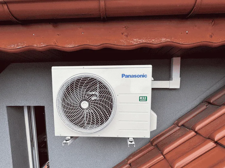 Jednostka zewnętrzna klimatyzatora Panasonic na ścianie obok czerwonej dachówki