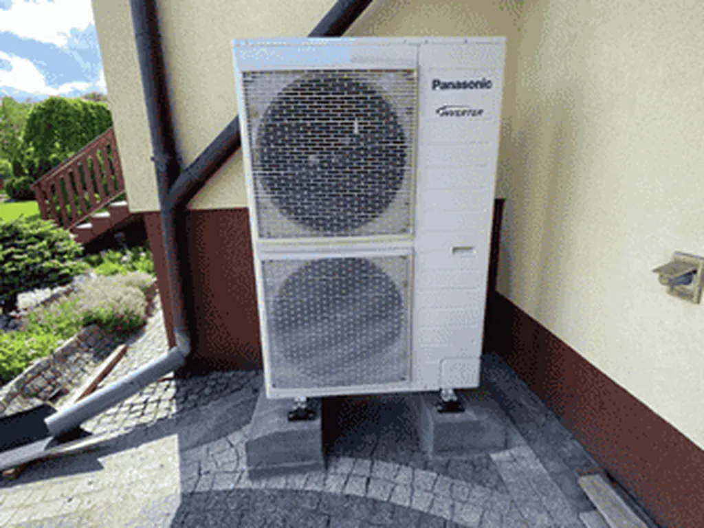 Pompa ciepła, Gołkowice: Jednostka zewnętrzna Panasonic Inverter przy kremowej ścianie, ogród z przyciętym krzewem