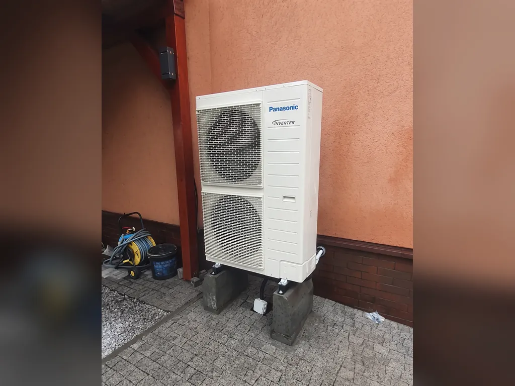 Pompa ciepła, Rybnik: Jednostka zewnętrzna Panasonic przy pomarańczowej ścianie, kostka