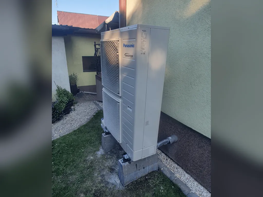 Pompa ciepła, Jastrzębie-Zdrój: Jednostka zewnętrzna przy kremowej ścianie, trawa