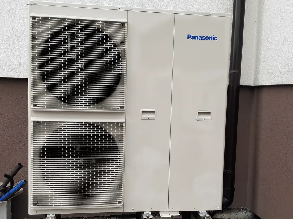 Pompa ciepła: Zbliżenie jednostki zewnętrznej Panasonic przy jasnej ścianie